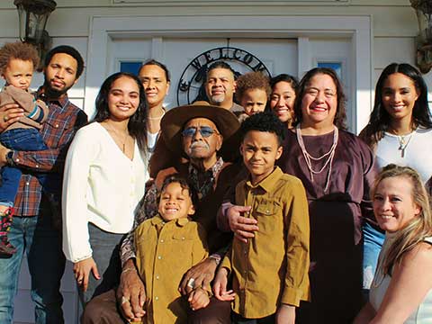 A family smiling with several generations depicted.